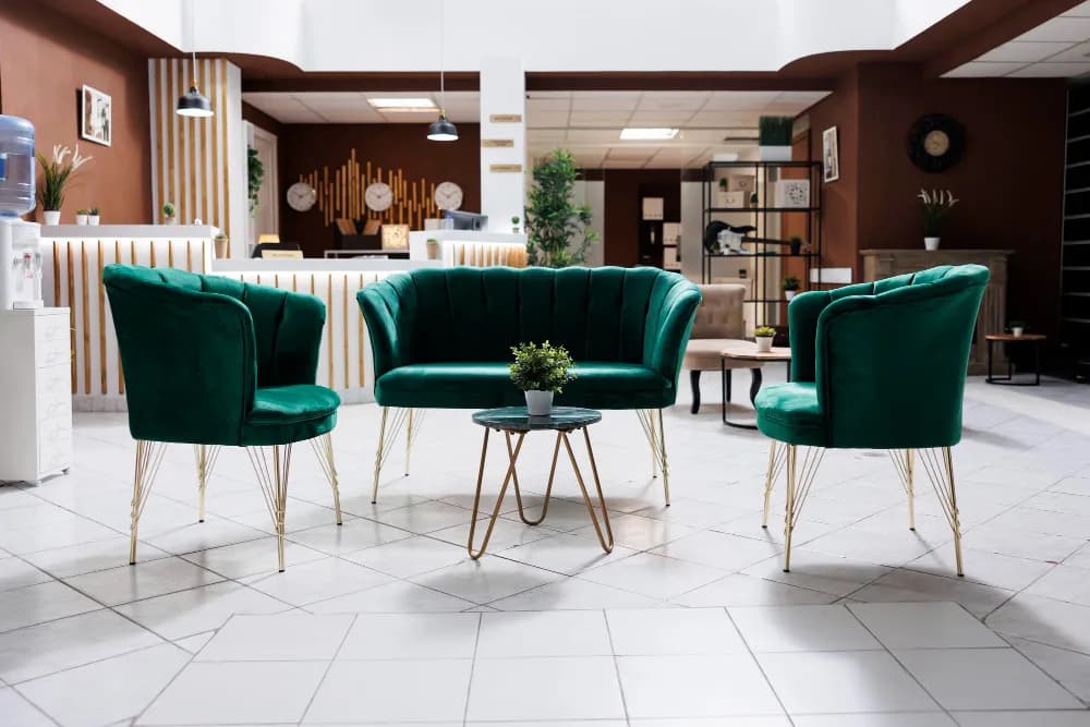 A green velvet loveseat and two matching armchairs around a small gold coffee table in a furniture showroom